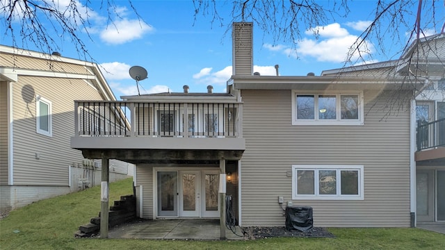 back of house featuring a patio area, a lawn, and a chimney