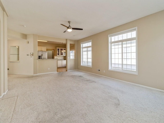 unfurnished living room featuring light colored carpet, baseboards, and ceiling fan