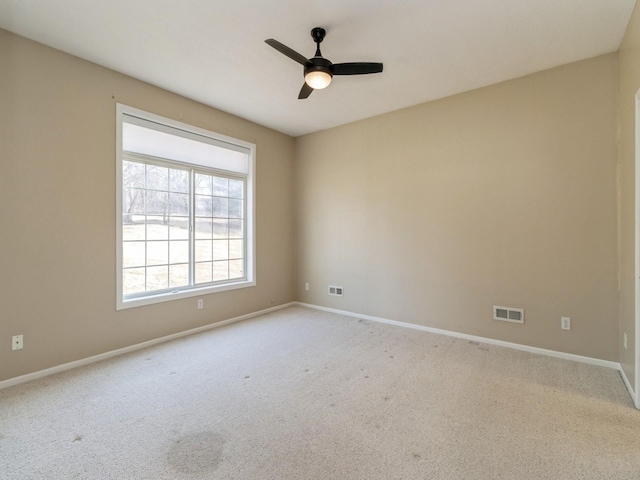 carpeted spare room with visible vents, a ceiling fan, and baseboards