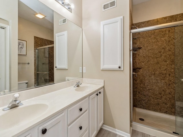 bathroom with a shower stall, double vanity, visible vents, and a sink