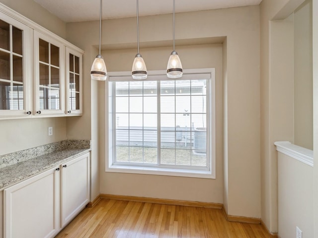 unfurnished dining area featuring light wood-style flooring and baseboards