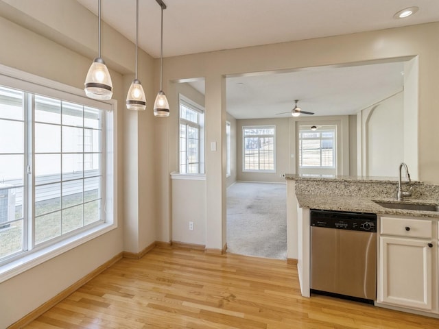 kitchen featuring light stone countertops, baseboards, a sink, light wood-style floors, and dishwasher