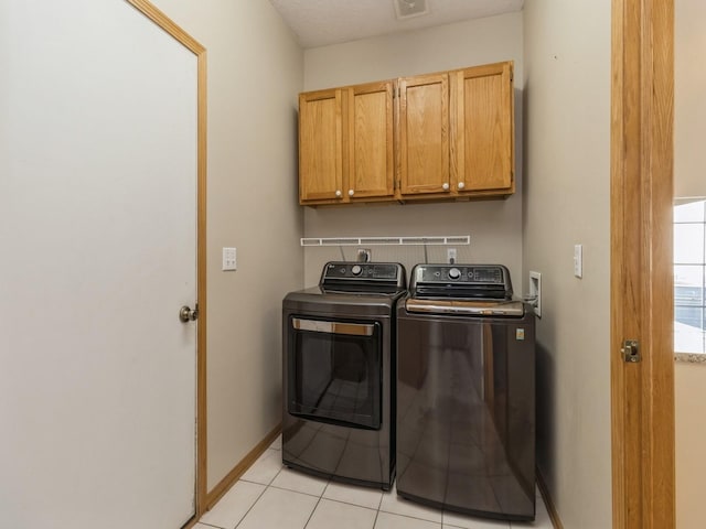 laundry area featuring visible vents, baseboards, washer and dryer, light tile patterned flooring, and cabinet space