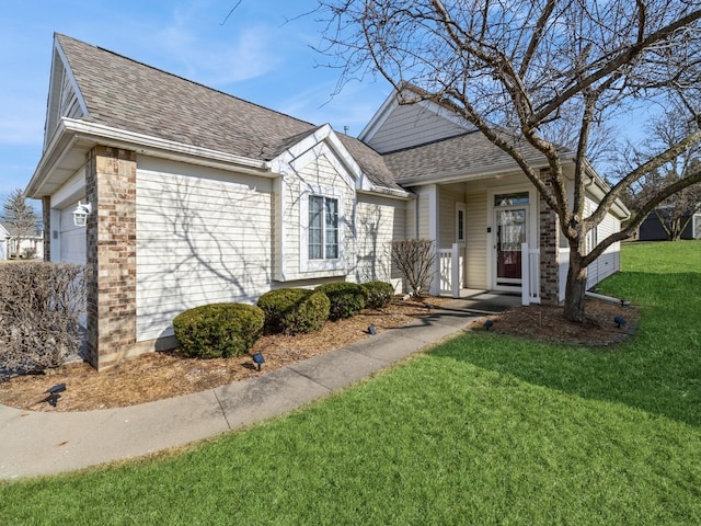 view of front of house with a garage, roof with shingles, and a front lawn