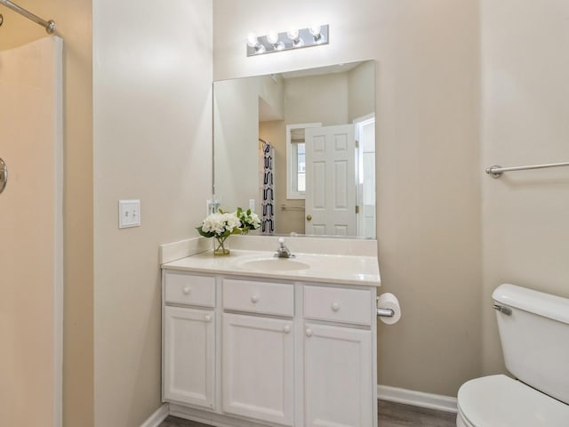 bathroom with a shower with shower curtain, baseboards, toilet, and vanity