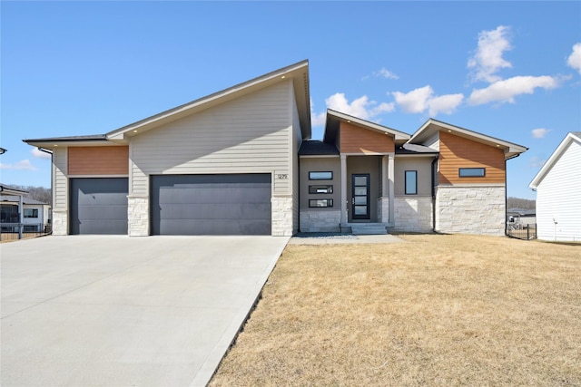 contemporary home featuring a garage, stone siding, a front yard, and driveway