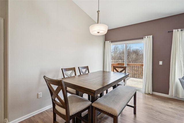 dining area featuring vaulted ceiling, baseboards, and light wood-type flooring