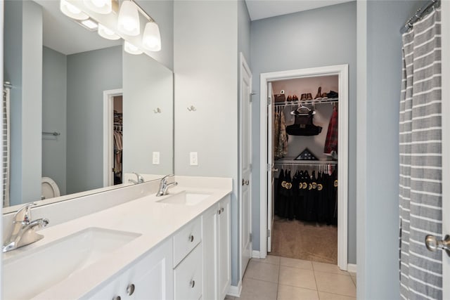 bathroom with a sink, baseboards, double vanity, and tile patterned floors