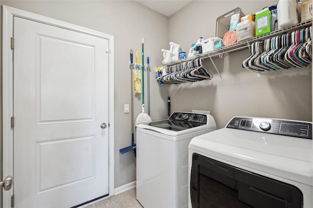 washroom with laundry area, washing machine and dryer, and baseboards