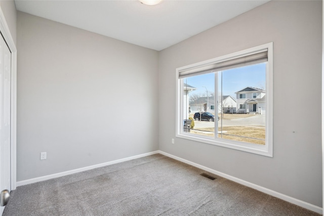 carpeted empty room featuring visible vents and baseboards