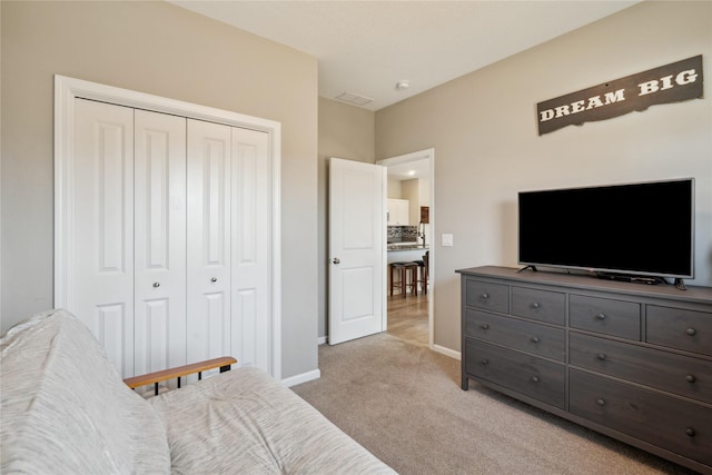 bedroom with a closet, baseboards, and light colored carpet