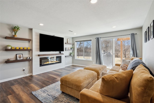 living area with baseboards, a large fireplace, a textured ceiling, and wood finished floors