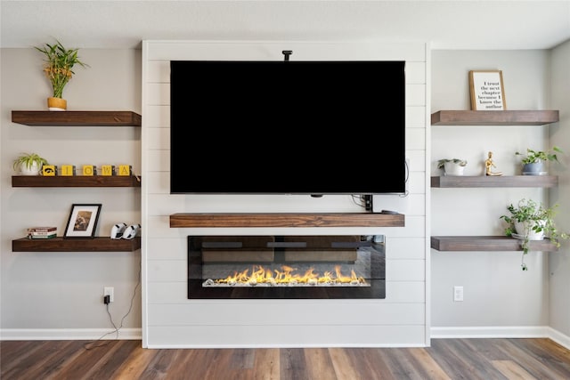 living area featuring a fireplace, baseboards, and wood finished floors