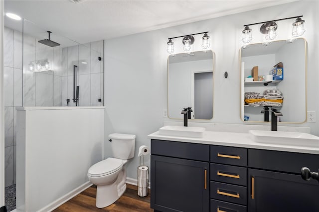 bathroom featuring a tile shower, double vanity, wood finished floors, and a sink