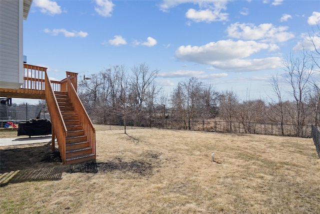 view of yard featuring stairway, a trampoline, a deck, and fence