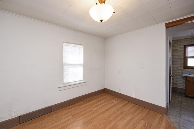 unfurnished room featuring visible vents, baseboards, a healthy amount of sunlight, and light wood-style flooring