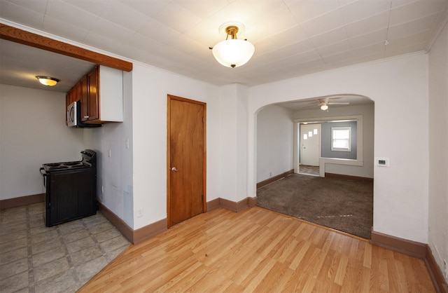 spare room featuring baseboards, light wood-type flooring, ornamental molding, arched walkways, and a ceiling fan