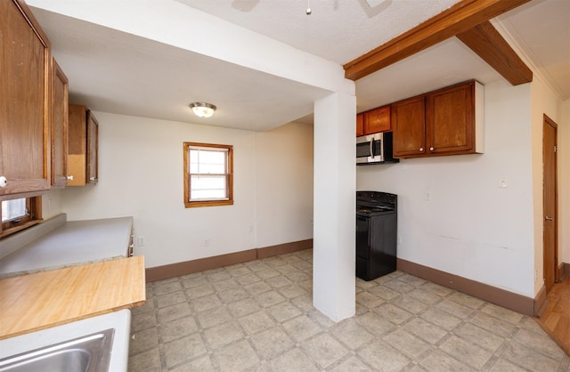 kitchen featuring beamed ceiling, brown cabinets, black range with electric stovetop, stainless steel microwave, and light floors