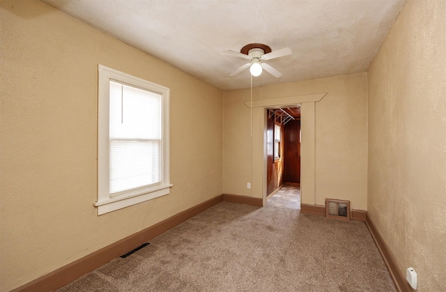 spare room with a textured wall, baseboards, visible vents, and carpet floors