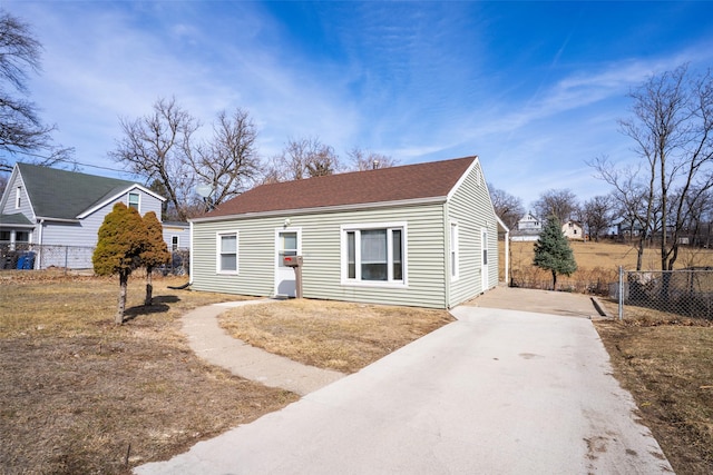 view of front facade featuring fence, driveway, and roof with shingles