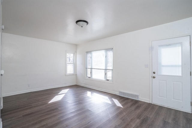 foyer with baseboards, visible vents, and dark wood-style flooring