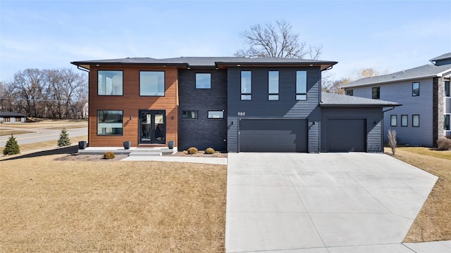 modern home featuring a garage, a front yard, driveway, and a shingled roof