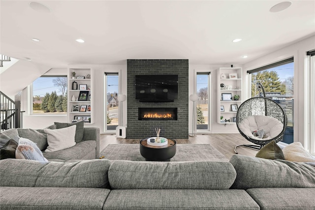 living room featuring a wealth of natural light, stairway, wood finished floors, and a fireplace