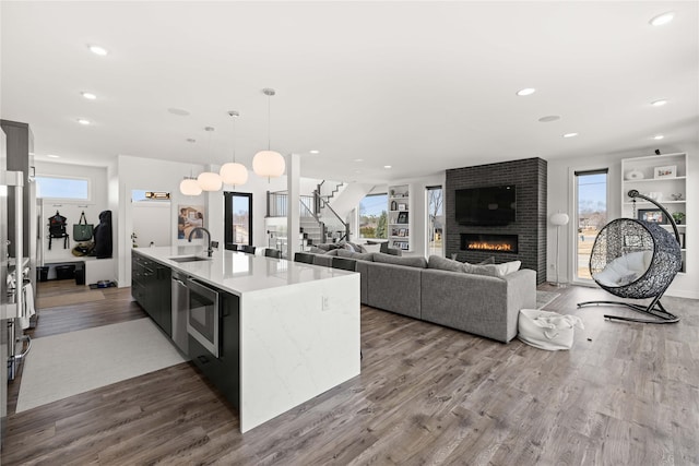 kitchen featuring recessed lighting, a fireplace, a sink, dark wood-type flooring, and decorative light fixtures