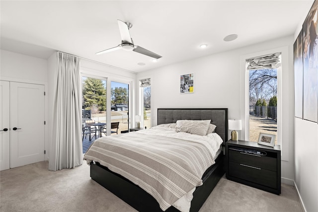 bedroom with light carpet, multiple windows, a ceiling fan, and access to exterior