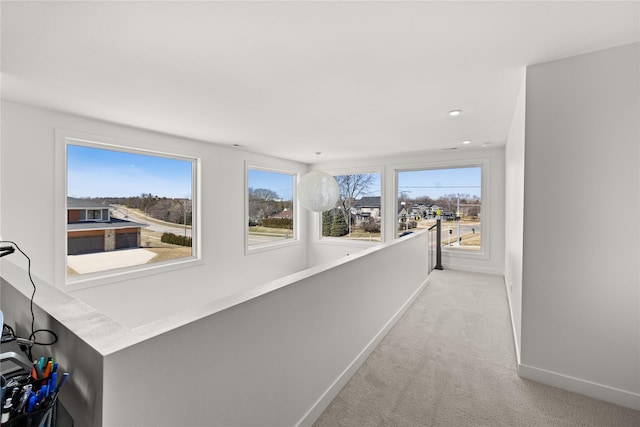 corridor featuring light carpet, recessed lighting, baseboards, and a wealth of natural light