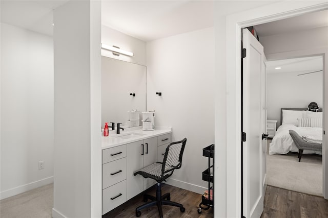 ensuite bathroom featuring baseboards, vanity, wood finished floors, and ensuite bathroom