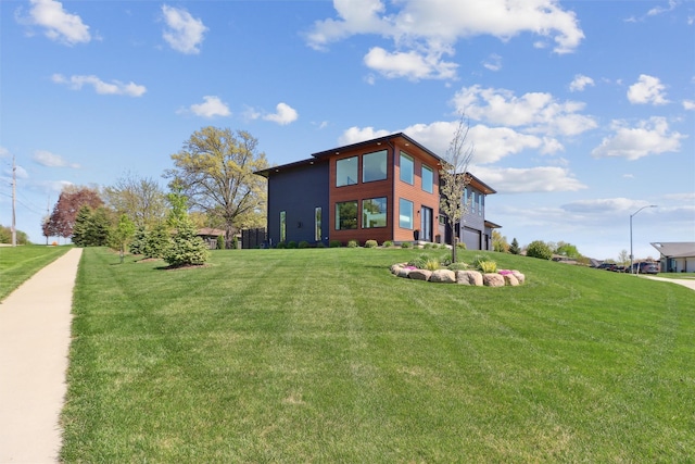 rear view of house featuring a lawn and a garage