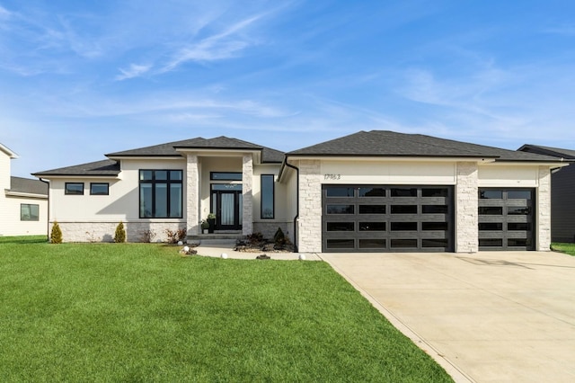 prairie-style house featuring a garage, stone siding, concrete driveway, and a front lawn