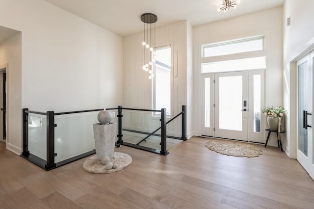 foyer with a high ceiling, an inviting chandelier, and wood finished floors