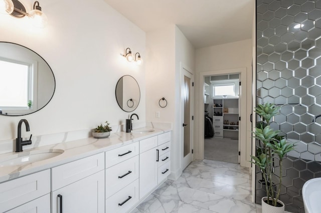 bathroom featuring double vanity, marble finish floor, a spacious closet, and a sink