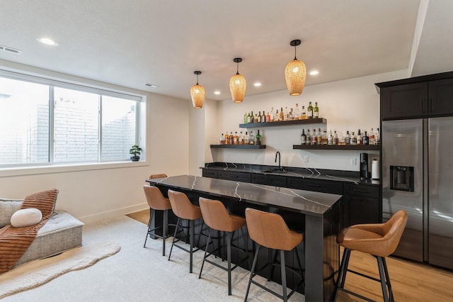 bar with baseboards, wet bar, recessed lighting, stainless steel fridge with ice dispenser, and a sink