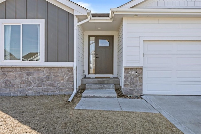 property entrance with stone siding, board and batten siding, and a garage