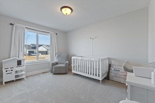 bedroom with a crib, carpet, baseboards, and a textured ceiling