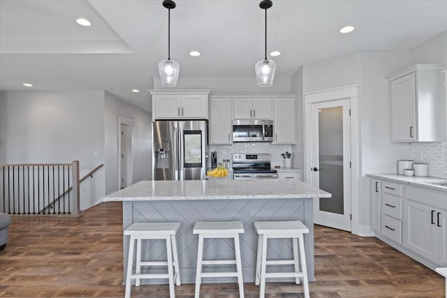 kitchen with dark wood finished floors, a kitchen breakfast bar, white cabinetry, and appliances with stainless steel finishes