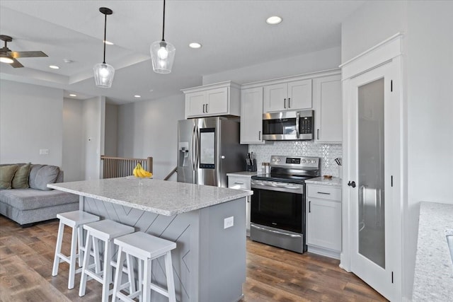 kitchen with dark wood-style floors, stainless steel appliances, decorative backsplash, open floor plan, and a center island