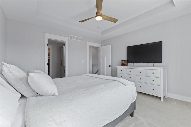 bedroom featuring visible vents, ceiling fan, baseboards, light carpet, and a raised ceiling