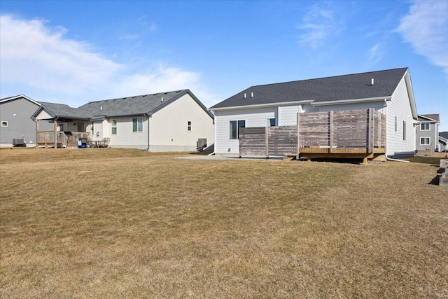 rear view of house with central AC unit, a lawn, and a wooden deck