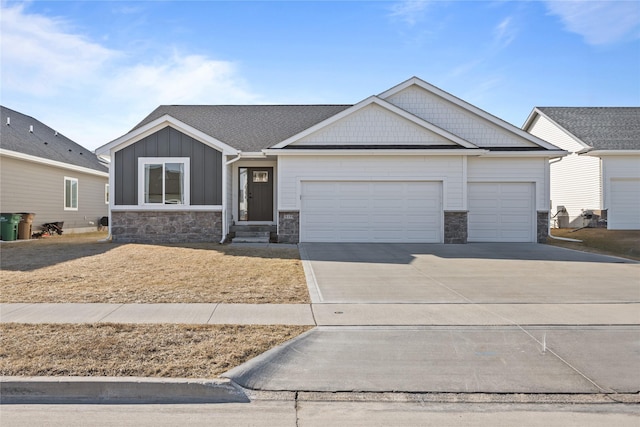 view of front of house featuring a garage, stone siding, board and batten siding, and driveway