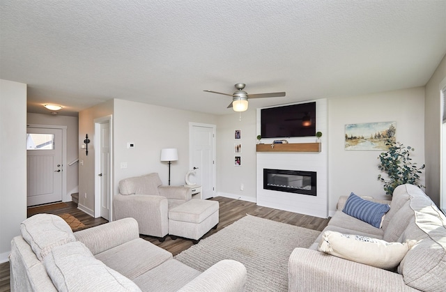 living room with a textured ceiling, a large fireplace, and wood finished floors