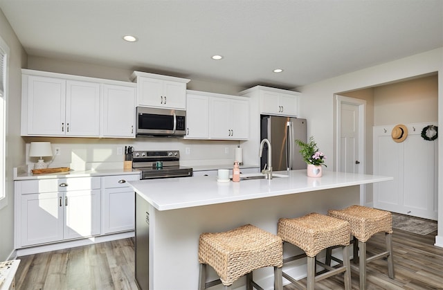 kitchen featuring light wood-style flooring, an island with sink, white cabinetry, appliances with stainless steel finishes, and light countertops