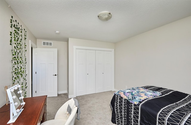 carpeted bedroom featuring baseboards, visible vents, a closet, and a textured ceiling