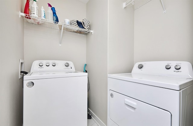 washroom featuring laundry area, separate washer and dryer, and baseboards