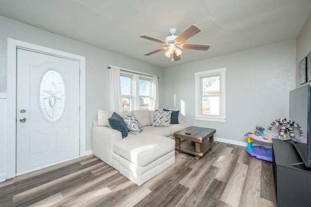 living area featuring baseboards, wood finished floors, and a ceiling fan