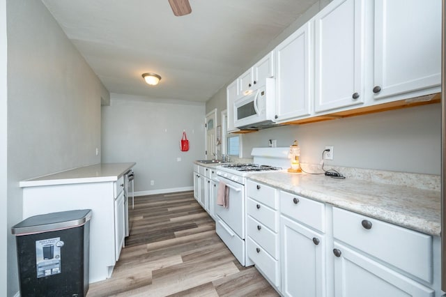 kitchen with baseboards, light countertops, light wood-style flooring, white cabinets, and white appliances