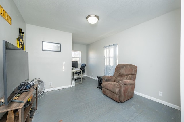 sitting room featuring baseboards, a textured ceiling, and concrete flooring